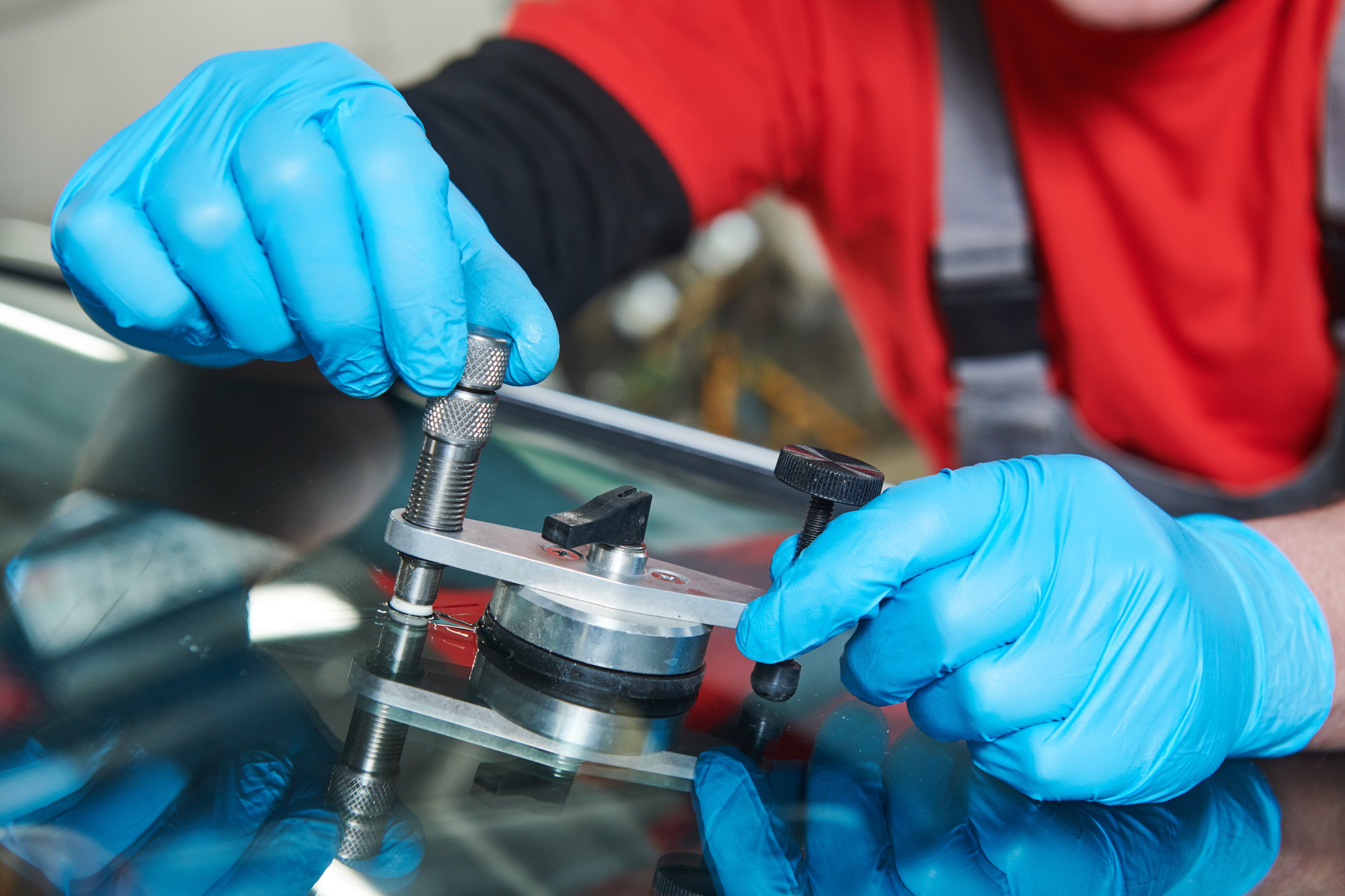 Technician using a resin bridge tool on a chipped windshield
