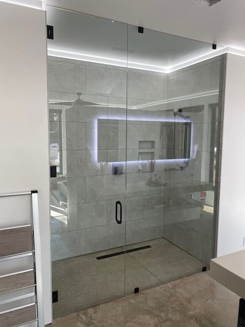 Corner shower installation with glass door and dark hardware