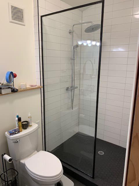 Frameless glass wet room with freestanding tub and herringbone tile