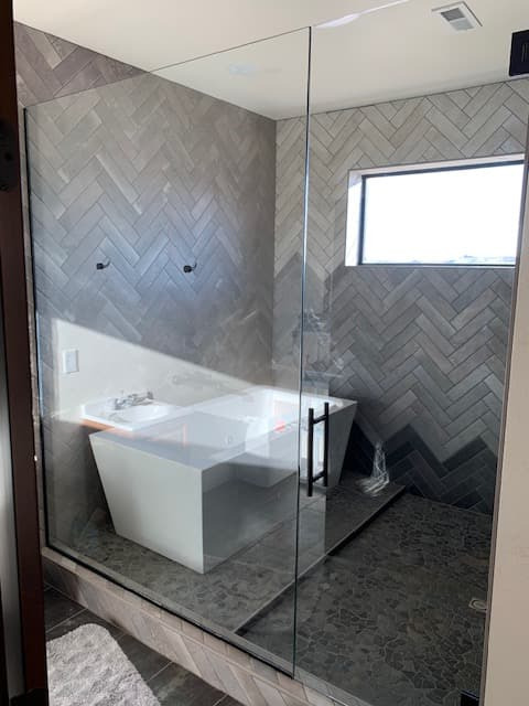 Frameless shower with gray subway tile, pony wall, and decorative niche