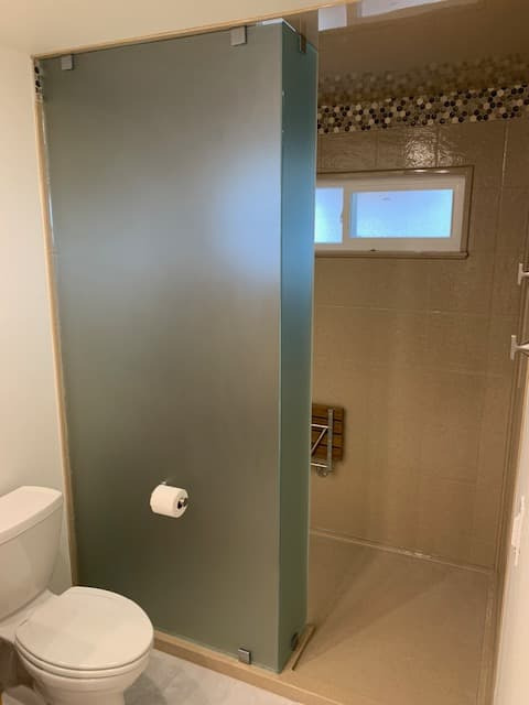 Walk-in shower with slate-look tile, pony wall, and black clips