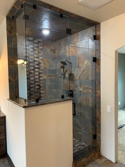 Frameless enclosure with pony wall, stone bench cap, and brushed metal hardware