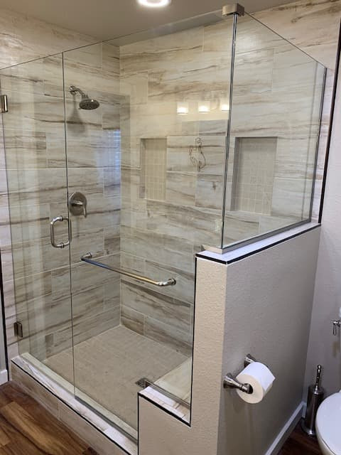 Triple glass shower bays with freestanding tub and marble-look tile
