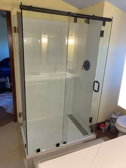 Walk-in shower with white subway tile, herringbone floor, and matte black fixtures