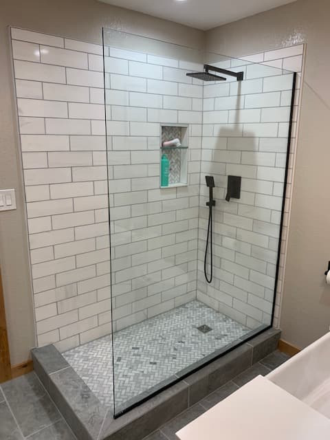 Minimal walk-in shower with large glass panel and matte black fixtures