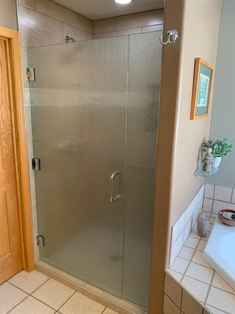 Neo-angle corner shower with dark framed glass and stone-look tile