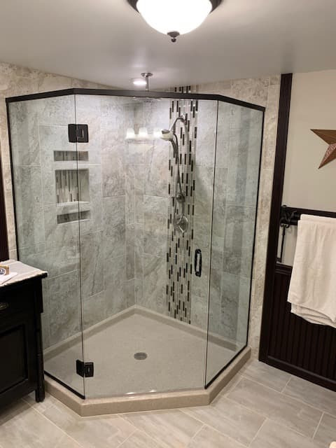 Corner shower with black metal grid over glass and built-in bench