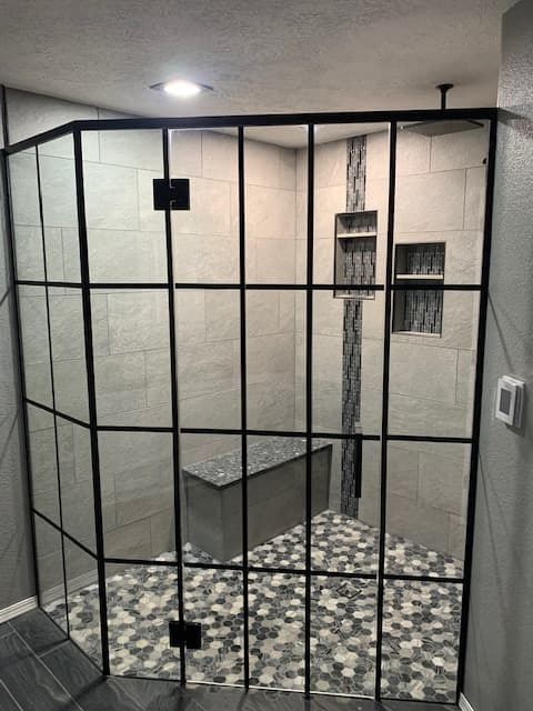 Marble-look tiled shower with glass door and gold-tone clips